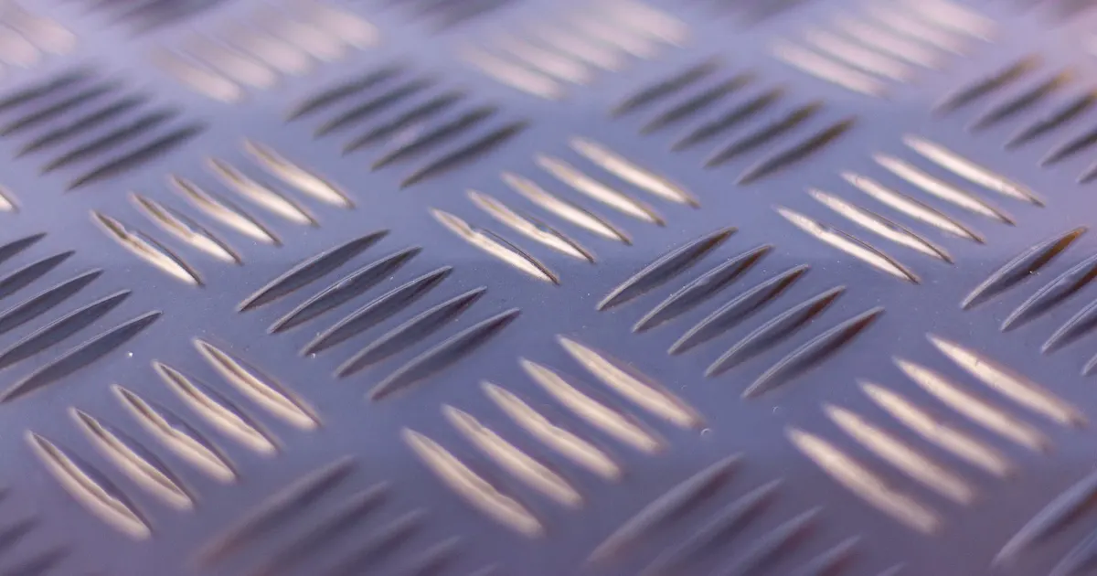 Close-up of a ribbed metal tread plate surface catching the light